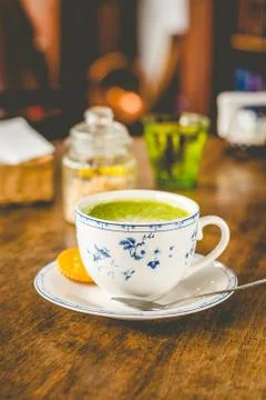 Green tea matcha soy latte in a china cup with brown sugar and a glass of wat Stock Photos