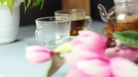 Green tea is poured into a cup from a transparent glass teapot. Dark blurred Stock Footage 152043941