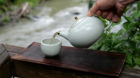 Green tea is poured in slow motion from a white ceramic teapot. Traditional tea Stock Footage 200385015