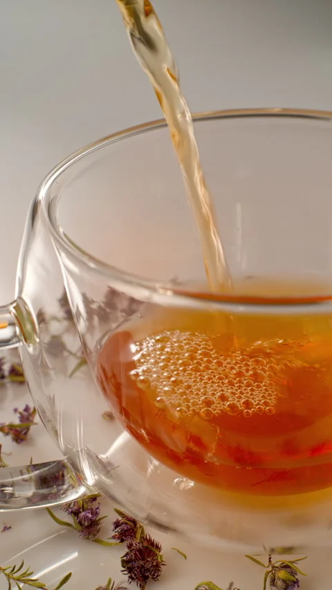 Green tea with thyme flowers is poured from glass mug. vertical video, close-up Video stock 310859866