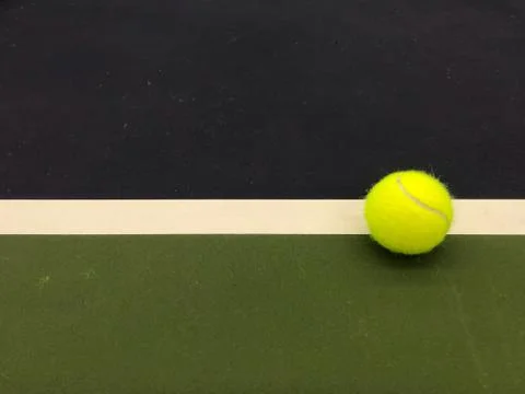 Green tennis ball at the right end white line of tennis court Stock Photos