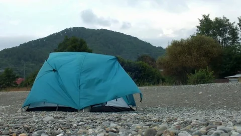 Green tent stands on a pebble beach in windy cloudy weather Stock Footage 108684022