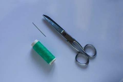 A green thread with a scissors and a needle Stock Photos
