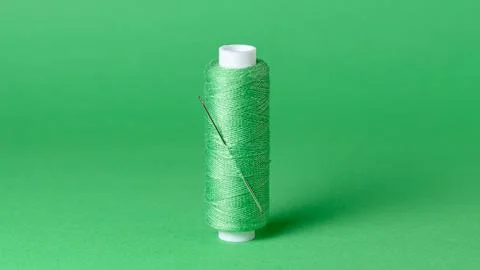 Green thread spool with needle close-up background Stock Photos