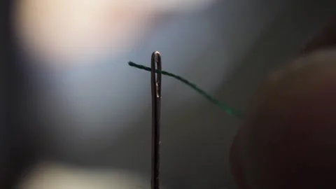 A green thread that is threaded through the eye of a needle. Macro Shot Stock Footage 287226921