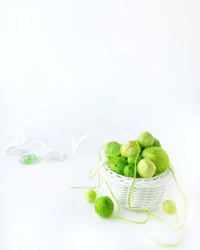 Green threads in a white wicker basket on a white background. Stock Photos