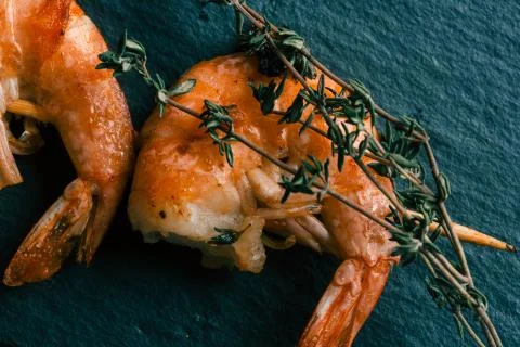 Green thyme sprig on the cooked headless prawns Stock Photos