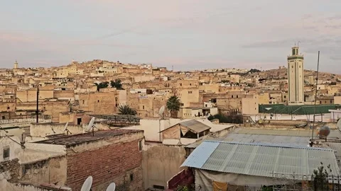 Green-tiled minaret over the Fez medina rooftops with satellite dishes at dusk, Stock Footage 344534541