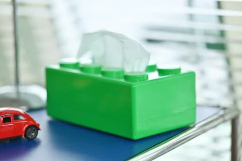 Green tissue box on blue surface with red toy car Stock Photos