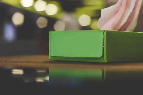 Green tissue box on reflective cafe table Foto stock