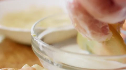 Green tomato slice dipped into a pale coating mixture, 4K Stock Footage 341119849