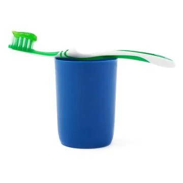 Green toothbrush with paste lying on blue plastic cup isolated over white Stock Photos