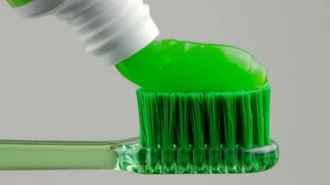 Green toothpaste is placed on a green toothbrush on a white background in close Stock Footage 147172054