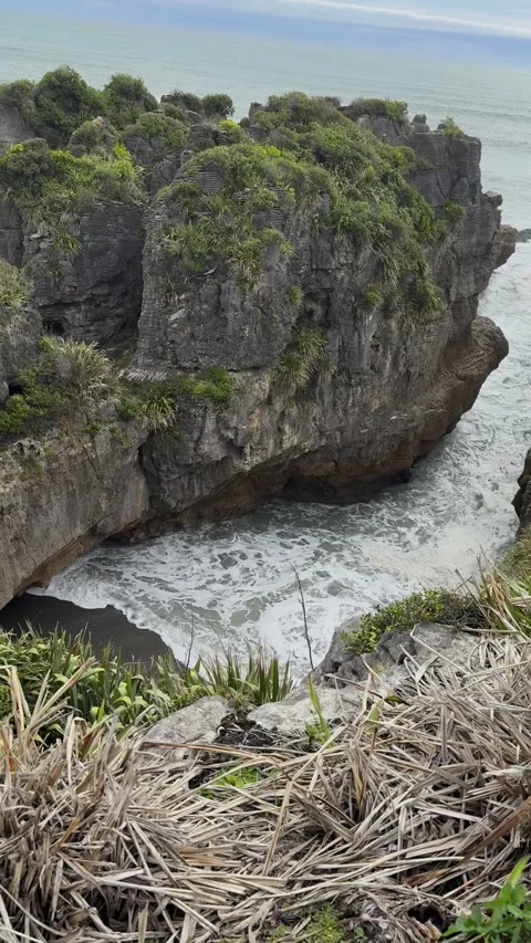 Green-topped limestone sea stack with surf swirling at its base Stock-Footage 348405435