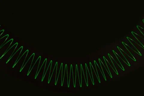 Green toy bouncing spring isolated on black background. Stock Photos