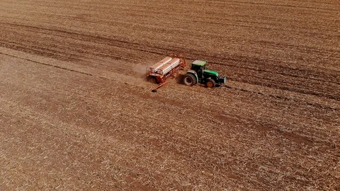 Green tractor in the field sows corn, aerial image Stock Footage 129847964