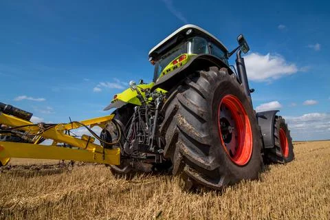 Green tractor in a field with stubble trailed equipment, bottom view Stock Photos