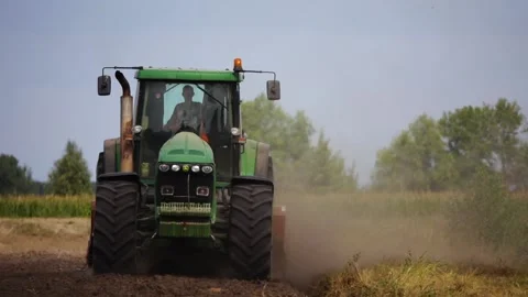 Green tractor with large wheels rides over the field and plow the soil after  Stock Footage 154160316