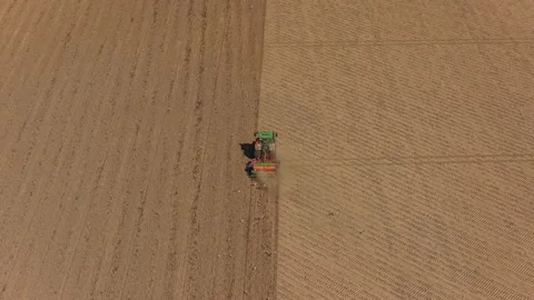 Green tractor plowing a vast brown field aerial view Stock Footage 342814486