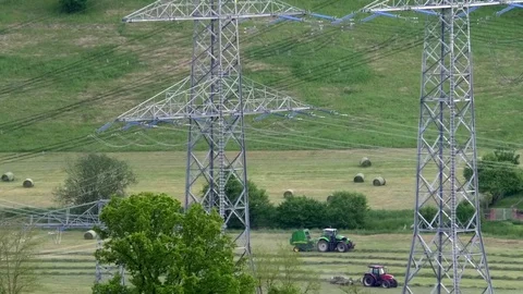 Green tractor producing a bale of straw, red tractor circulating hay, farming Stock Footage 76796241
