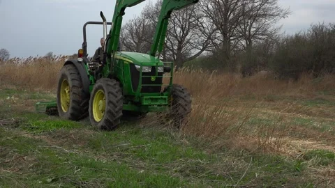 Green Tractor Pulling Brush Hog Mower Through Tall Grass on an Ontario Farm Stock Footage 346962055