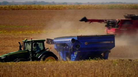 A green tractor pulls a blue grain cart through the harvest Stock Footage 345530614