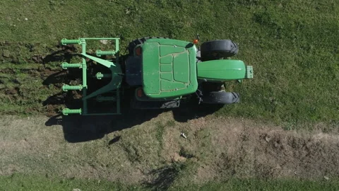 Green tractor pulls ripper tiller to loosen compacted topsoil, aerial Video stock 333632345