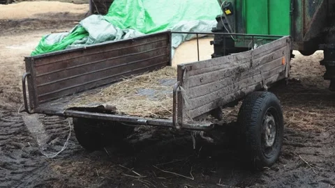 A green tractor pulls a trailer loaded with hay on a rural road Video stock 332226087