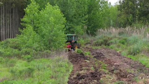 Green tractor with red plow working wet and muddy Delta del Paraná field Vídeo Stock 309510362
