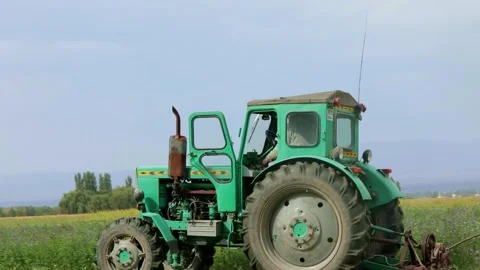 Green tractor rides across the field Stock Footage 255425480