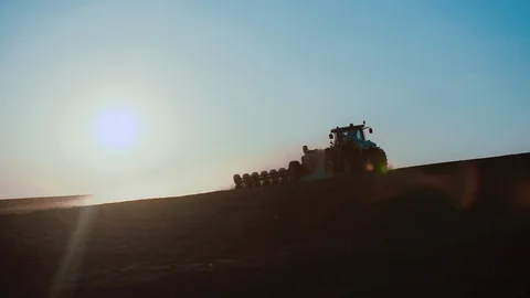 Green tractor with a seeder goes across the field, carried out by spring seeding Stock-Footage 128366169