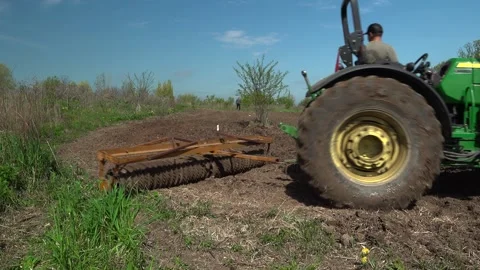 Green Tractor Towing a Cultipacker Executing a Turn on a Plowed Farm Field Stock Footage 346965096