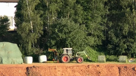 Green tractor unloading a wrapped hay bale, working farmer, agriculture, work Video stock 111785435