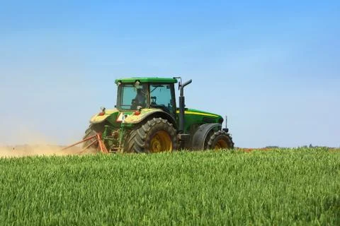 Green tractor working in the field. Stock Photos