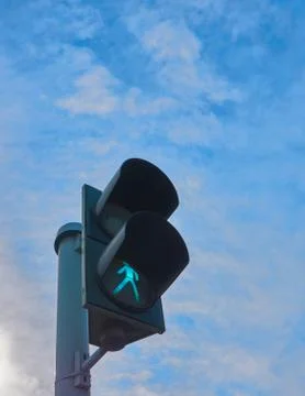 Green traffic light with clouds in background Stock Photos