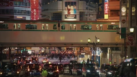 Green Train Passing Over Shibuya Crossing as Pedestrians Cross, Tokyo Stock Footage 340865603