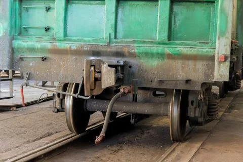 Green train wagon on the tracks inside a railway workshop during the day Foto stock