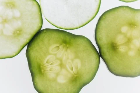 Green translucent slices of cucumber on the background of bright white light  Stock Photos