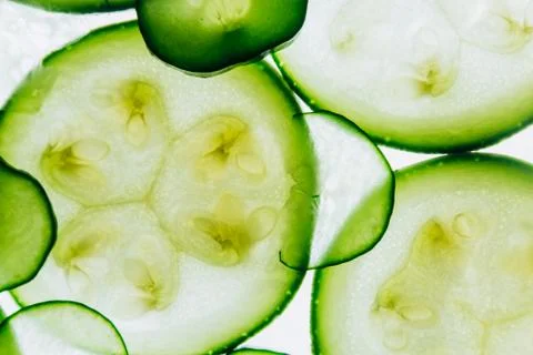 Green translucent slices of cucumber on the background of bright white light  Stock Photos