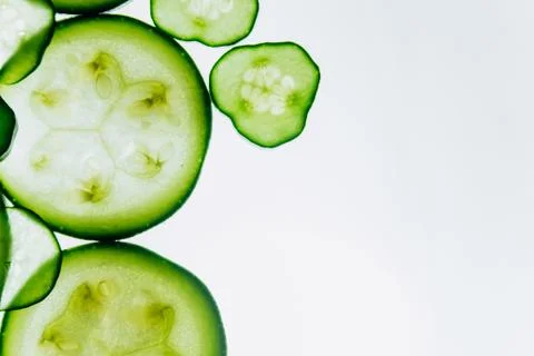 Green translucent slices of cucumber on the background of bright white light  Stock Photos
