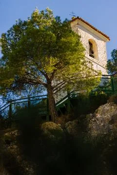 Green tree, church and bell tower under a clear blue sky. Stock Photos