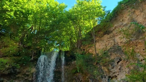 Green trees frame a waterfall cascading down rocky cliffs. Veliki Buk, Serbia. Stock Footage 336888486