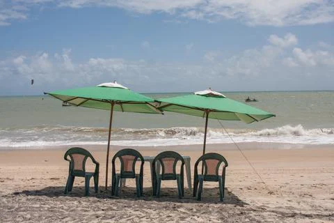 Green umbrellas set up with a small table at the beach Stock Photos