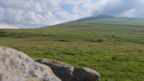 Green valley and mountain range with rocks in foreground Vidéo 311406286