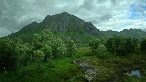 Green valley, birch trees, and dramatic steep mountain peak in Senja Norway Stock-Footage 342340416