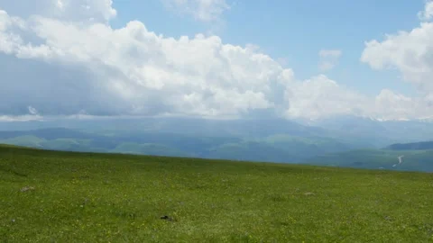 Green valley with distant mountains under a cloudy sky Stock Footage 310353192