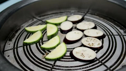 Green vegetable marrow or zucchini and eggplants are grilled over an open fire Stock Footage 302092932