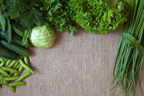 Green vegetables composition frame on rustic sackcloth background. Peas, cabbage Stock Photos
