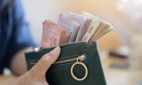 Green wallet with many Thai notes in Asian businesswoman hand for personal .. Foto stock