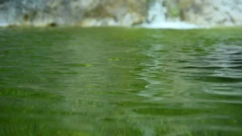Green water of a pool next to a waterfall in the mountains (slow motion) Stockbeeldmateriaal 211761699
